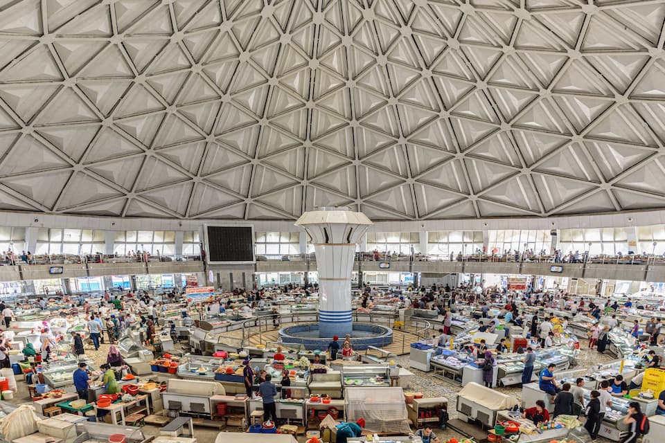 A large indoor market with a high, geometric ceiling and numerous stalls selling various goods.