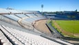 A large, empty stadium with tiered seating and a football field.