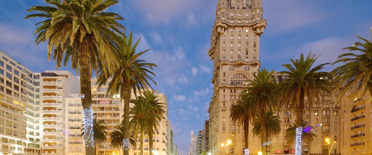 A tall, ornate building with intricate architectural details, surrounded by palm trees and modern buildings.