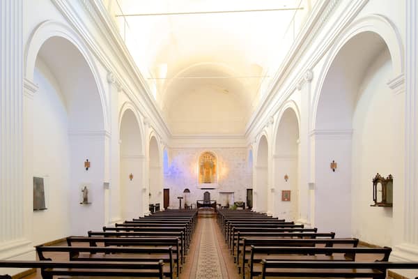 A church interior with rows of pews, arched ceilings, and a central altar.