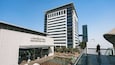 Un bâtiment moderne, sur lequel on peut lire l’inscription « ENTRÉE DU CENTRE DE CONGRÈS », et devant lequel se trouve une grande fontaine.