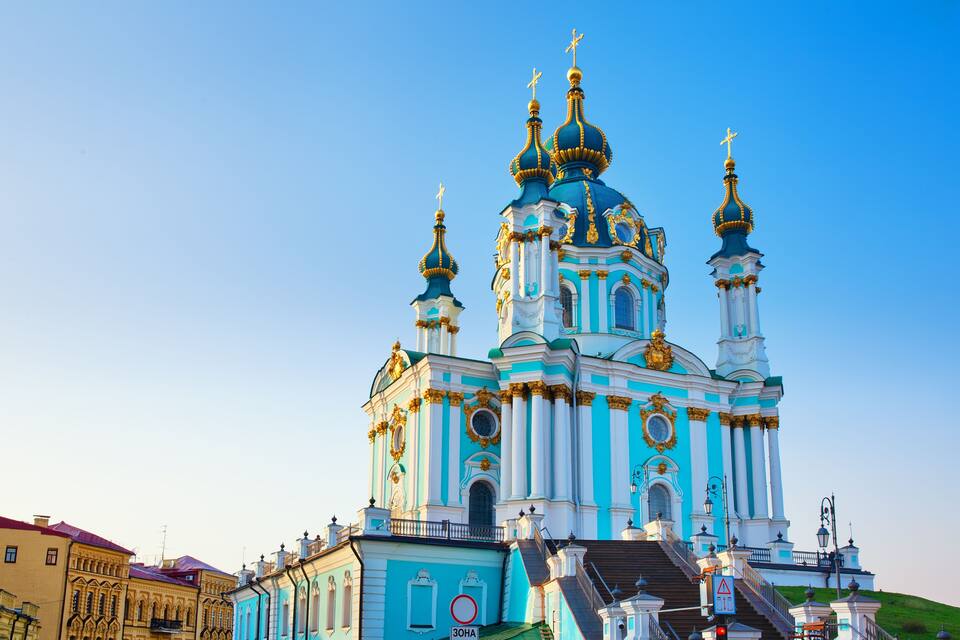 A large, ornate church with multiple domes and golden accents, surrounded by buildings.