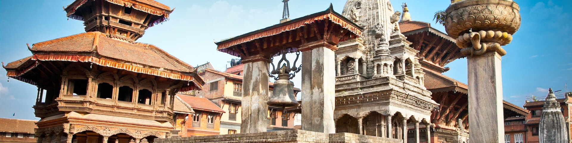 Un complejo histórico de templos con arquitectura intrincada, que incluye una destacada torre de campanas y una estatua de una deidad.
