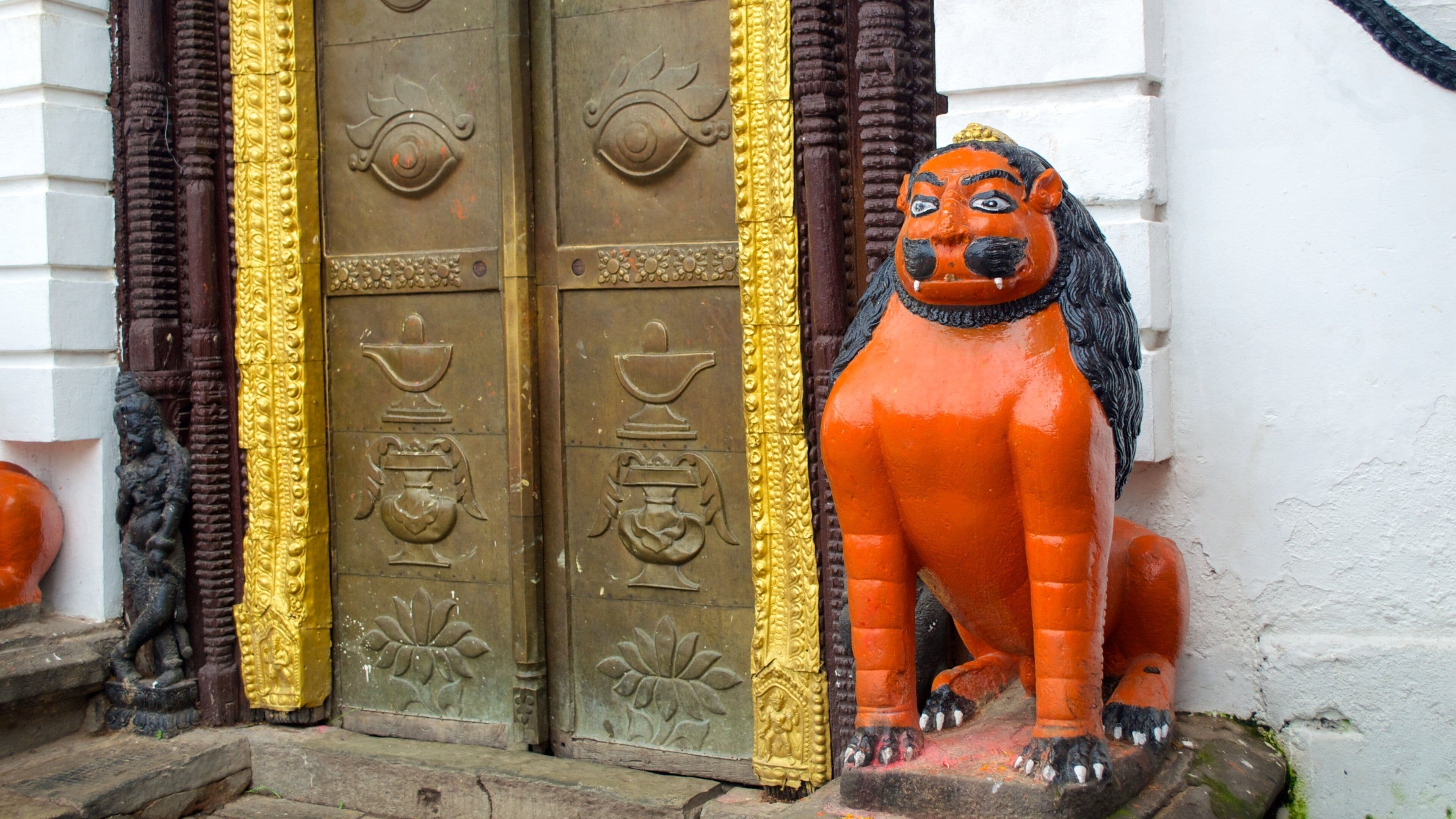 A statue of a lion next to a door with intricate carvings.