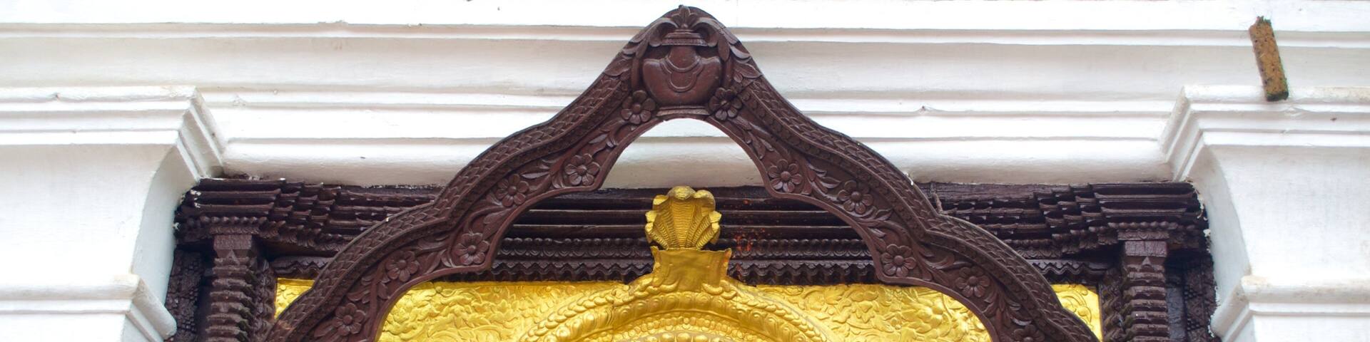 A detailed architectural entrance with ornate carvings and a golden arch.