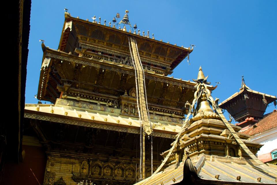 A traditional multi-tiered temple with ornate golden decorations and a prominent central spire.