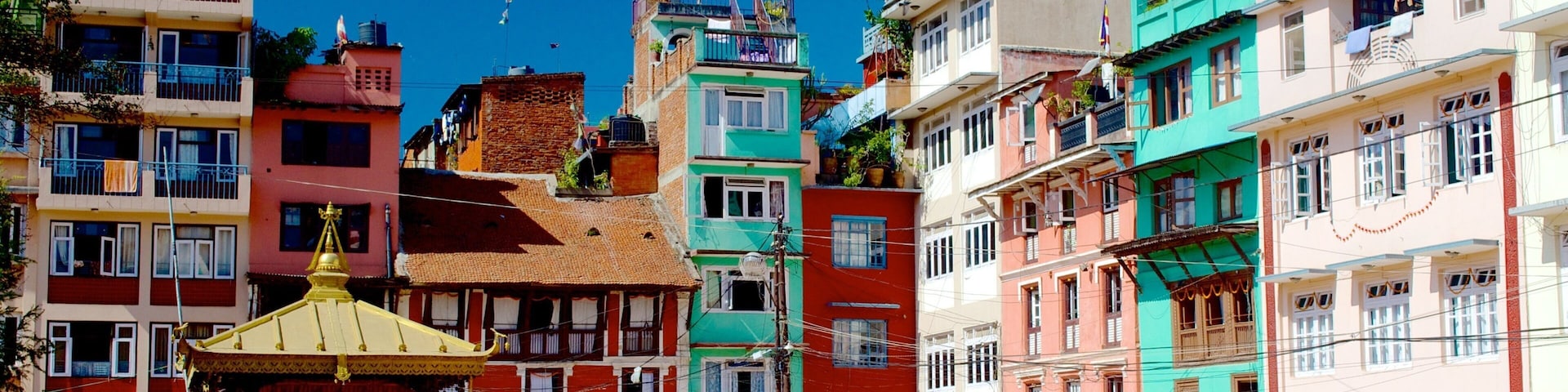 A colorful street with traditional buildings, a small shrine, and people walking.