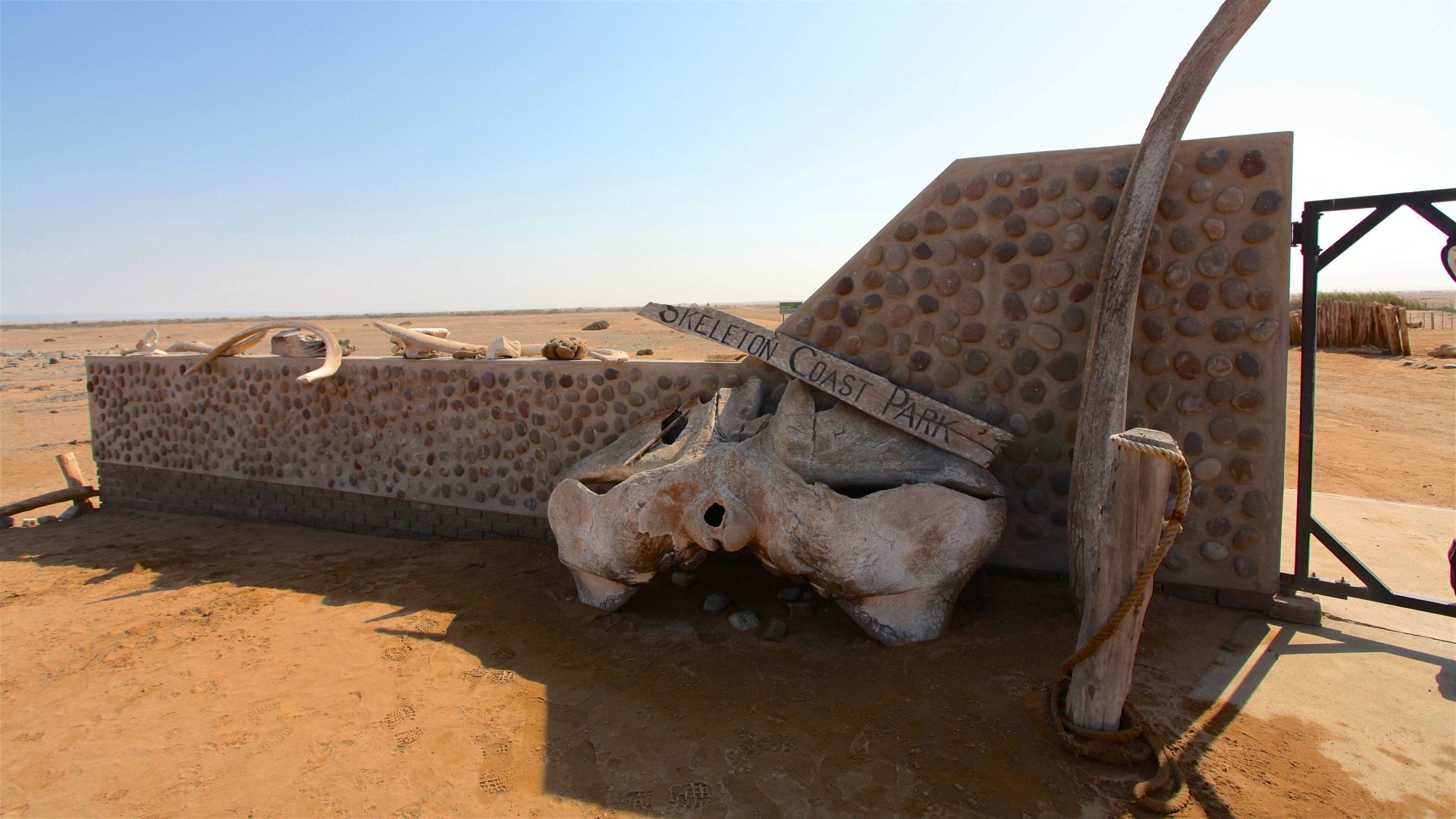 A desert landscape with a large, textured wall labeled "Skeleton Coast Park" and a large skull structure.