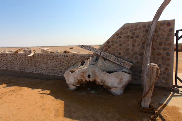 A desert landscape with a large, textured wall labeled "Skeleton Coast Park" and a large skull structure.