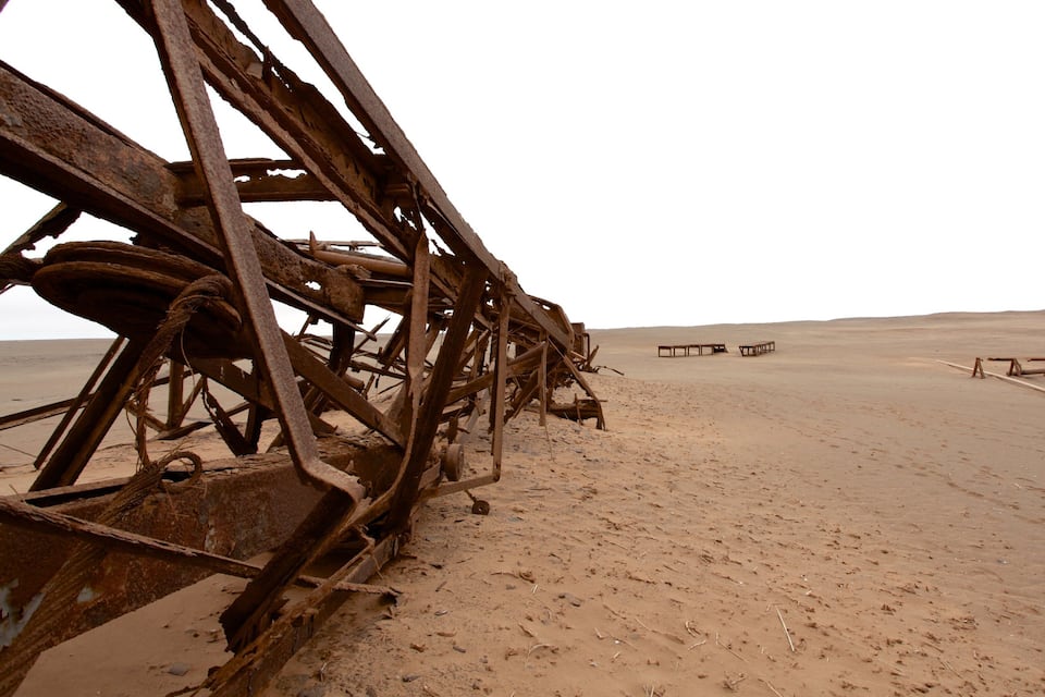 A rusted metal structure in a desert with a flat horizon.