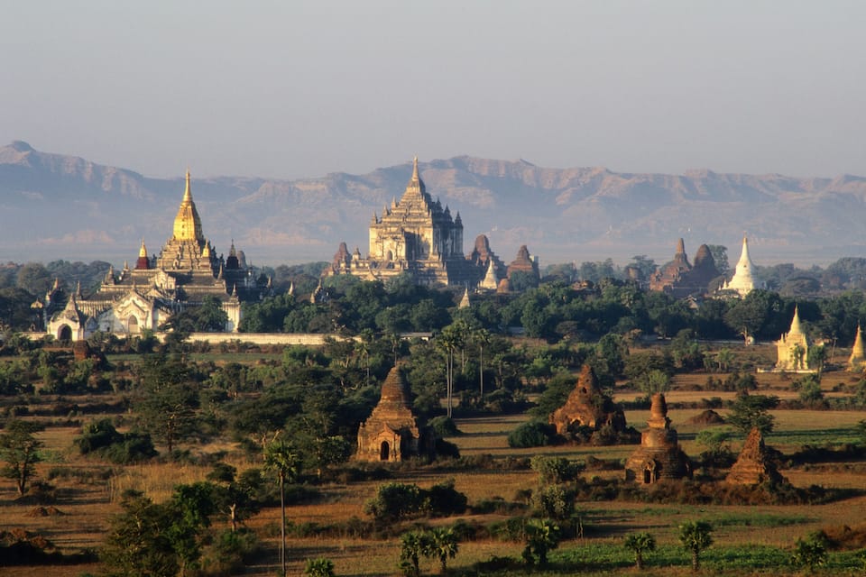 A landscape of ancient temples and pagodas surrounded by lush greenery and mountains.