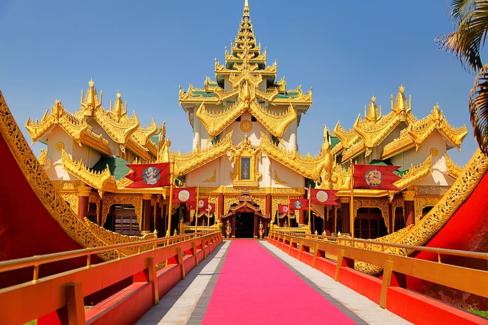 A golden temple with intricate architecture and a red carpet leading to the entrance.