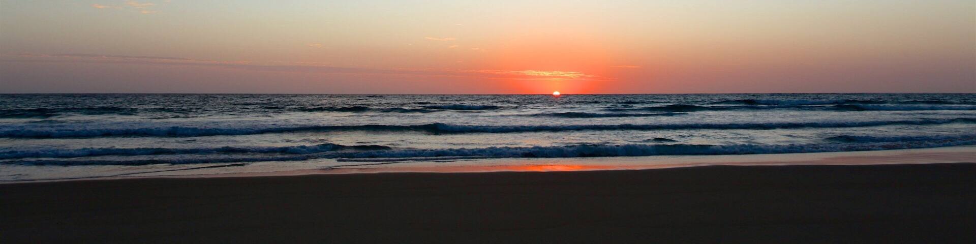 Tofo Beach which includes a sunset, a beach and general coastal views