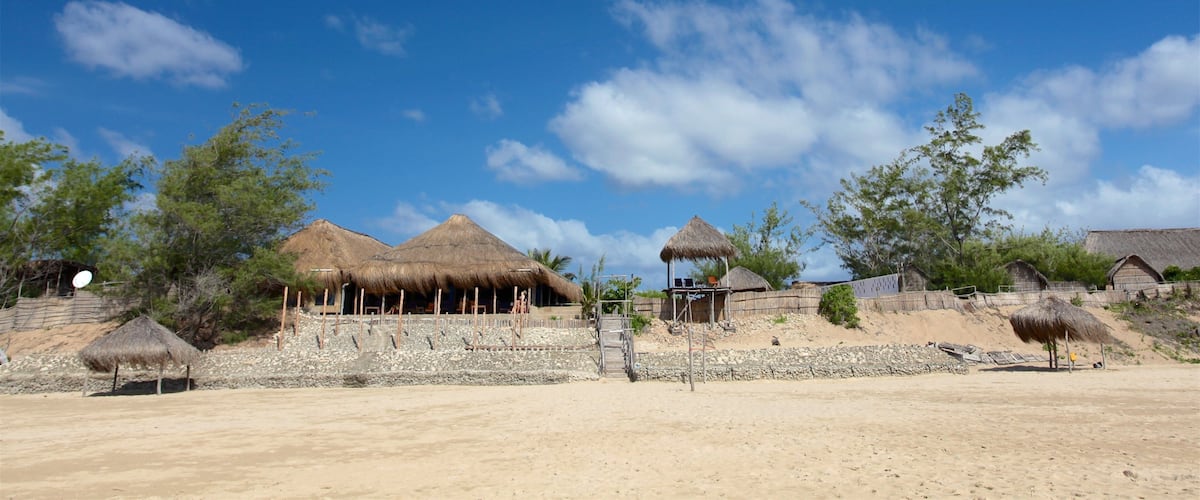 A desert landscape with thatched-roof huts and sparse vegetation.