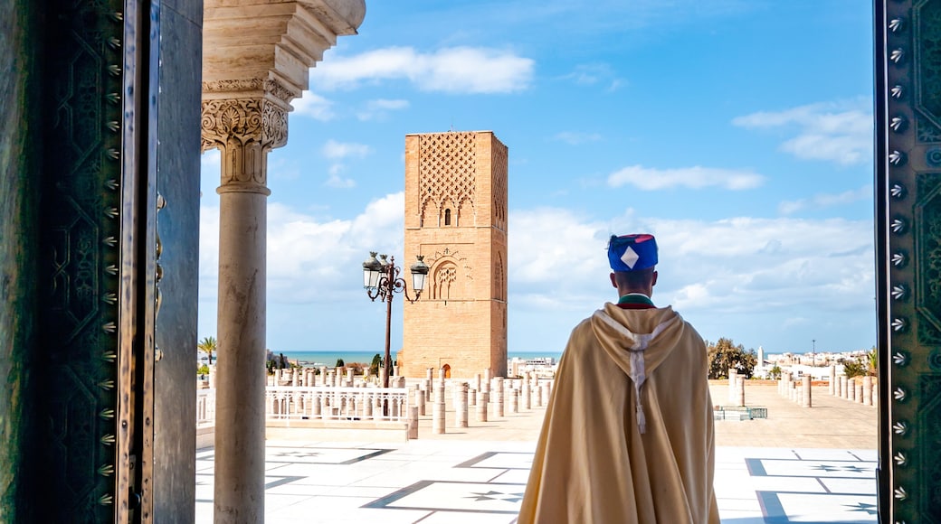 Guard soldier in national costume at the entrance of Mausoleum of Mohammed V and square with Hassan tower in Rabat on sunny day. Location: Rabat, Morocco, Africa