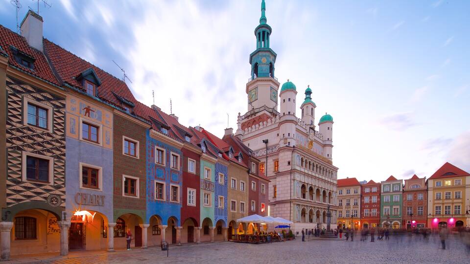 A historic square with colorful buildings, a prominent church with a clock tower, and a cobblestone plaza.