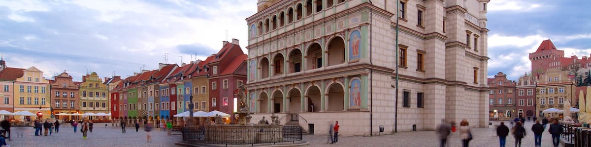 Ein historisches Gebäude mit einem Glockenturm und farbenfrohen Fassaden auf einem öffentlichen Platz.