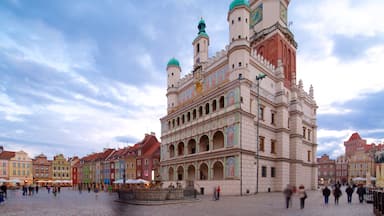 A historic building with a clock tower and colorful facades in a public square.