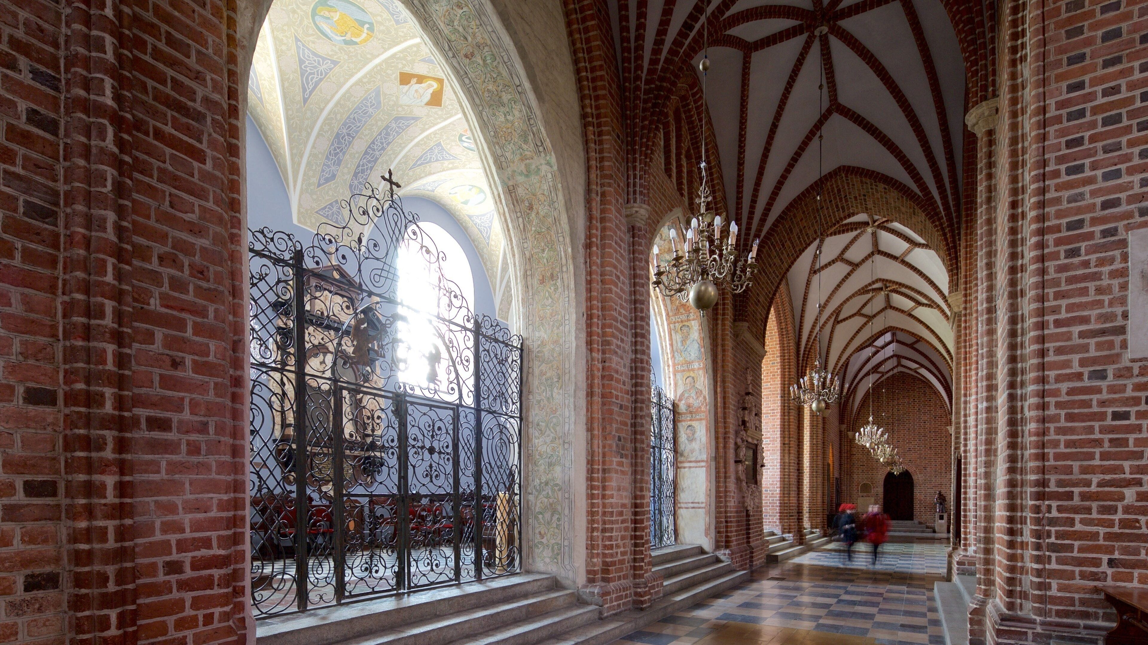 A cathedral interior with arched ceilings, brick walls, and ornate ironwork.