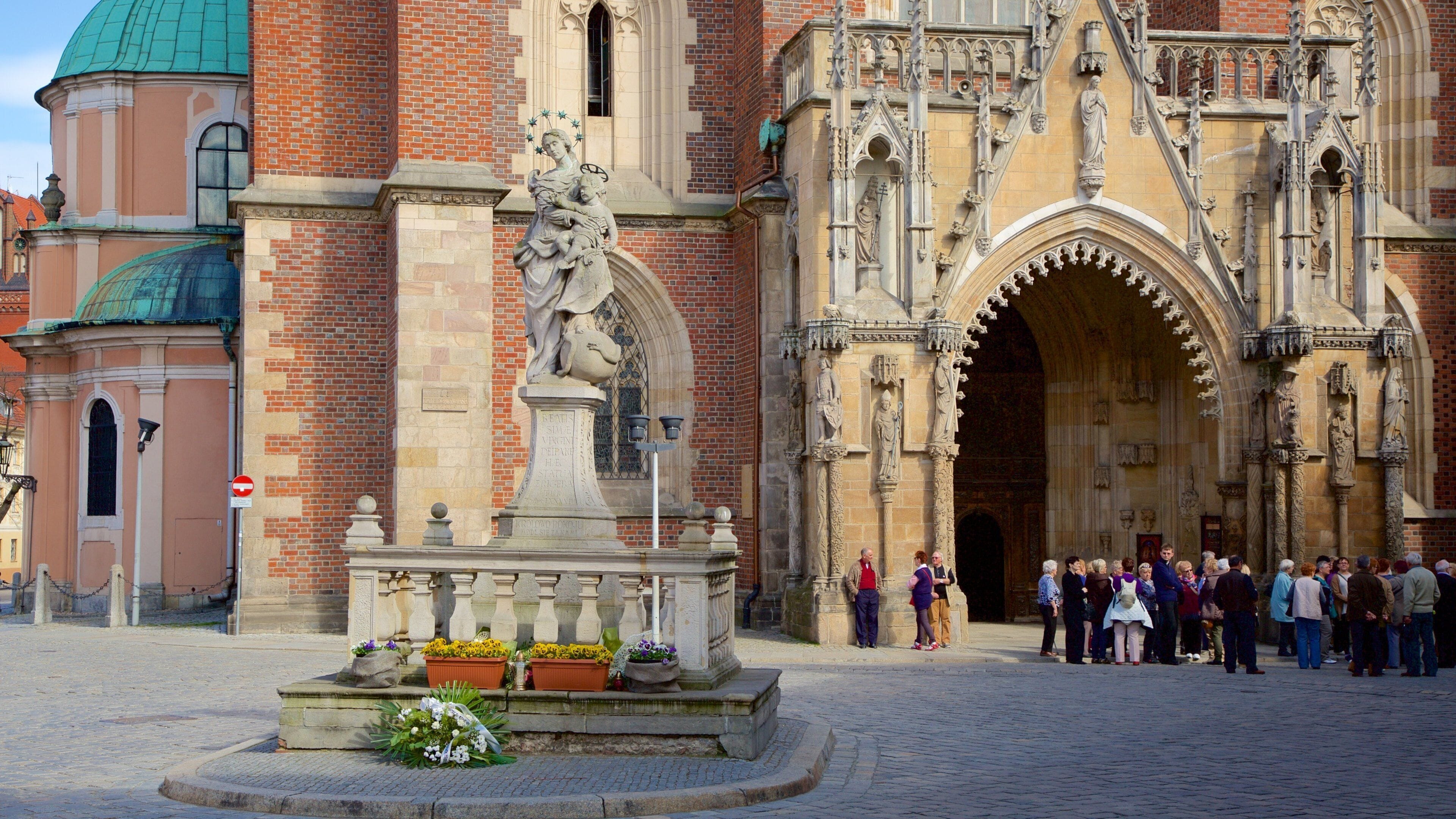 A historic church with intricate Gothic architecture, a statue, and a crowd of people.