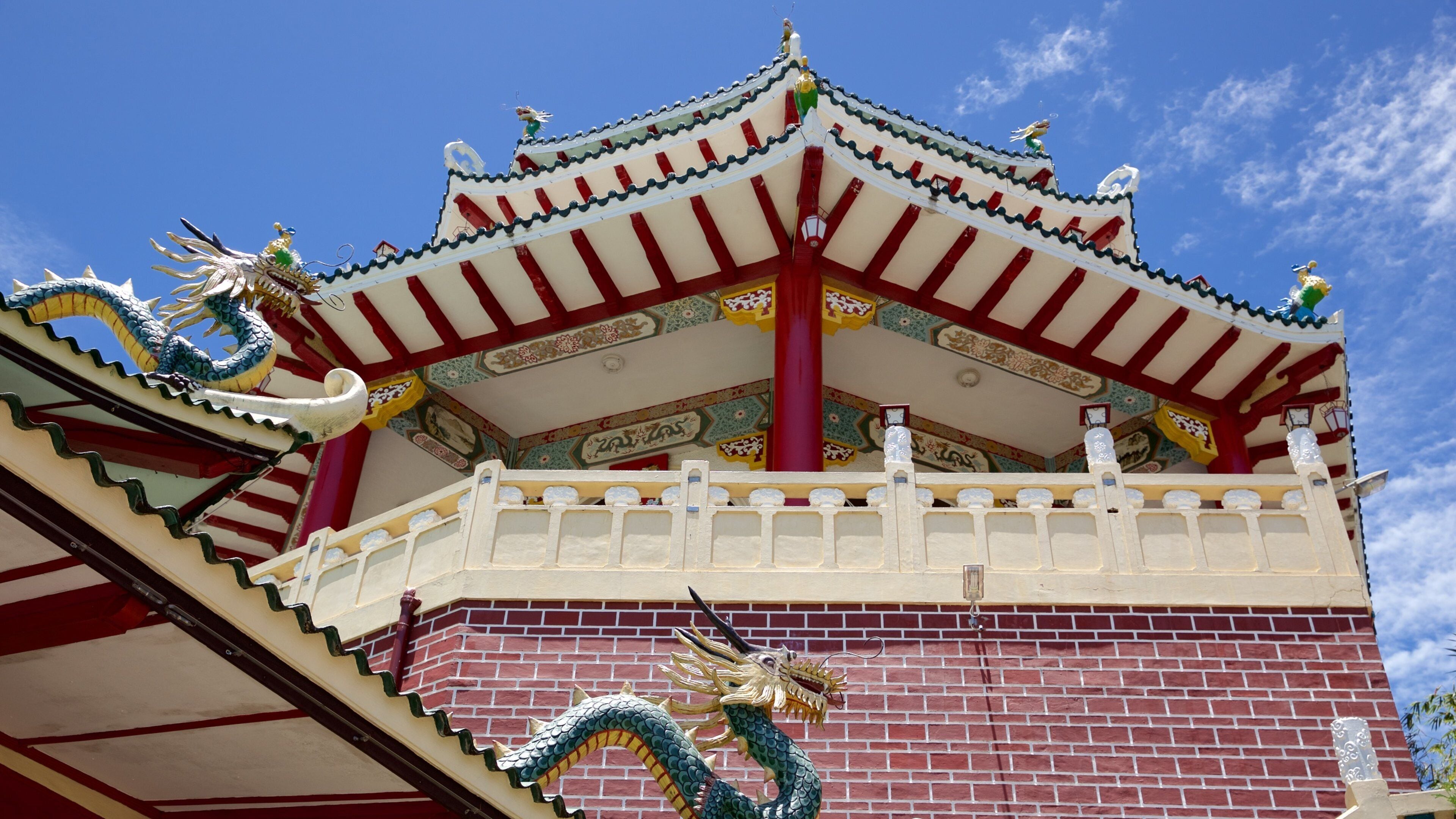 A traditional Chinese building with ornate dragon sculptures and red and white walls.