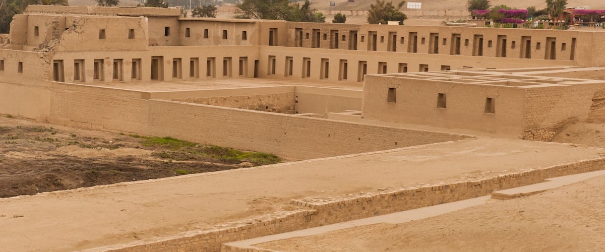 A desert landscape with ancient ruins featuring rectangular structures and stone walls.
