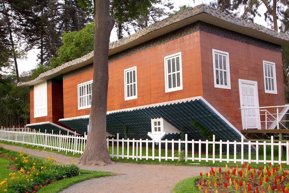 A traditional house with a white picket fence, surrounded by a garden with colorful flowers.