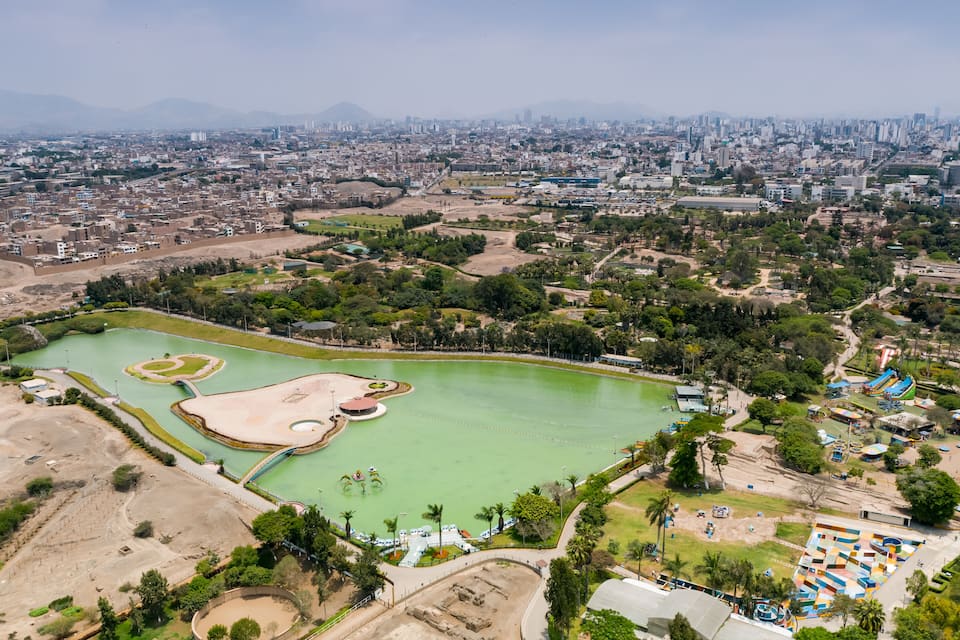 Une vue aérienne d’une ville avec un grand parc verdoyant, un stade et une aire de jeux colorée.