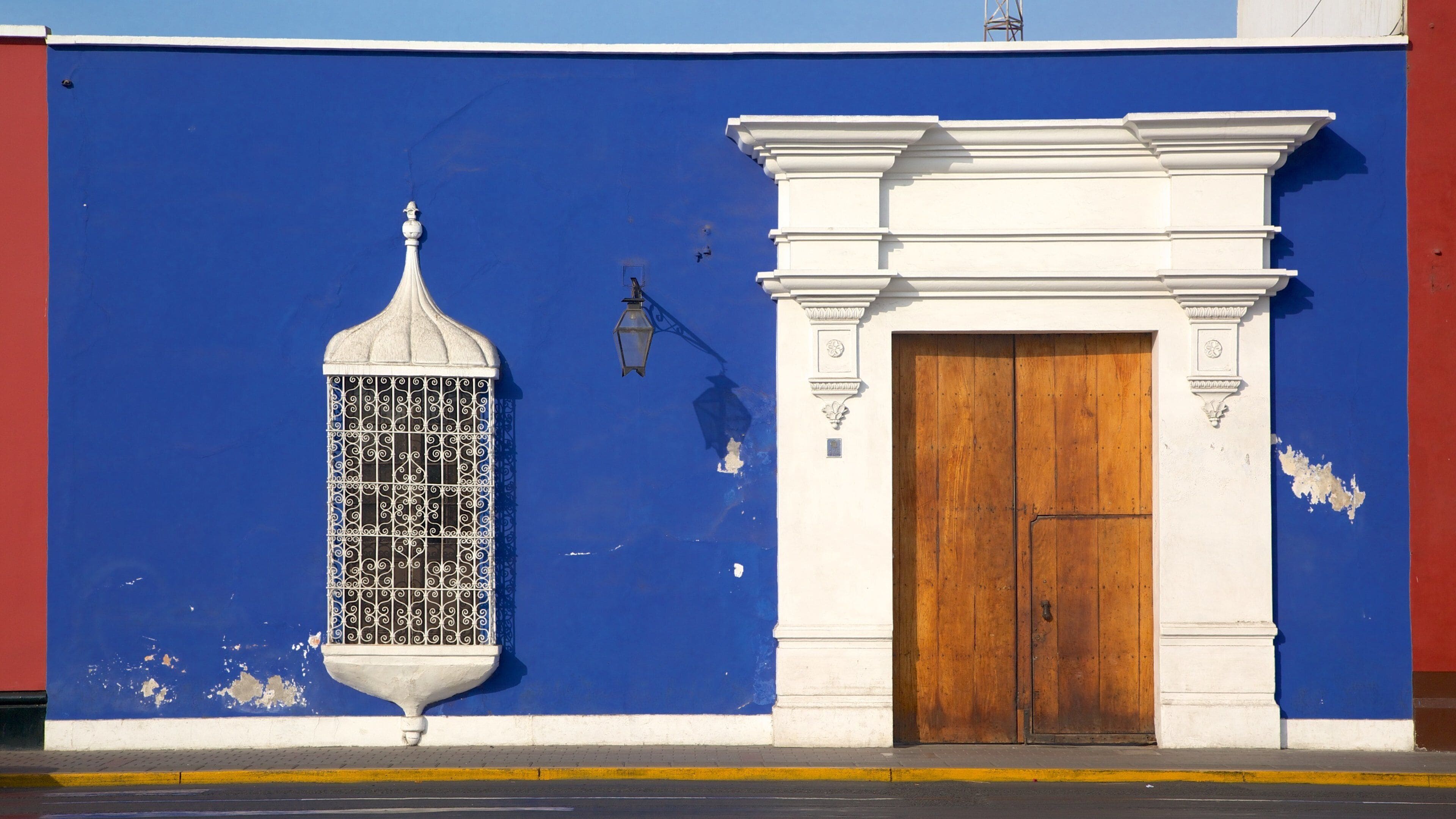 A blue wall with a white door and a decorative window.