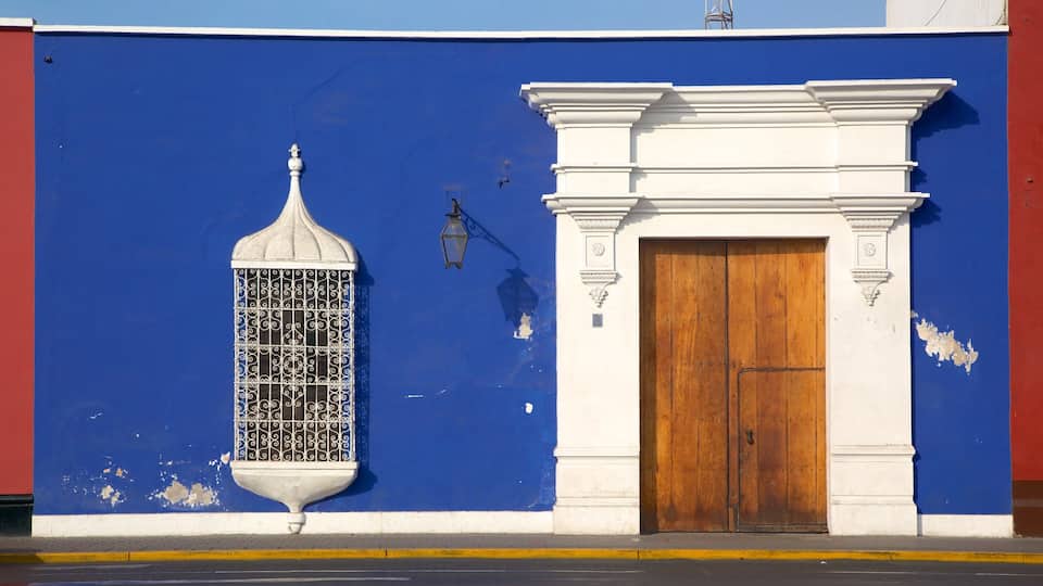 A blue wall with a white door and a decorative window.