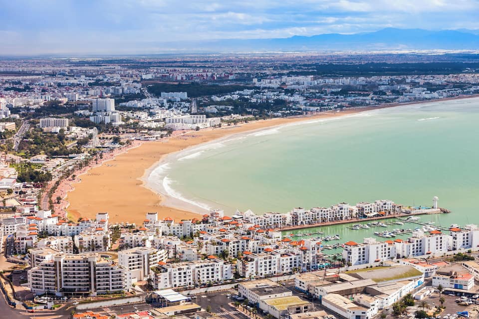 Un paysage urbain côtier avec une vaste plage, des immeubles résidentiels denses et une marina.