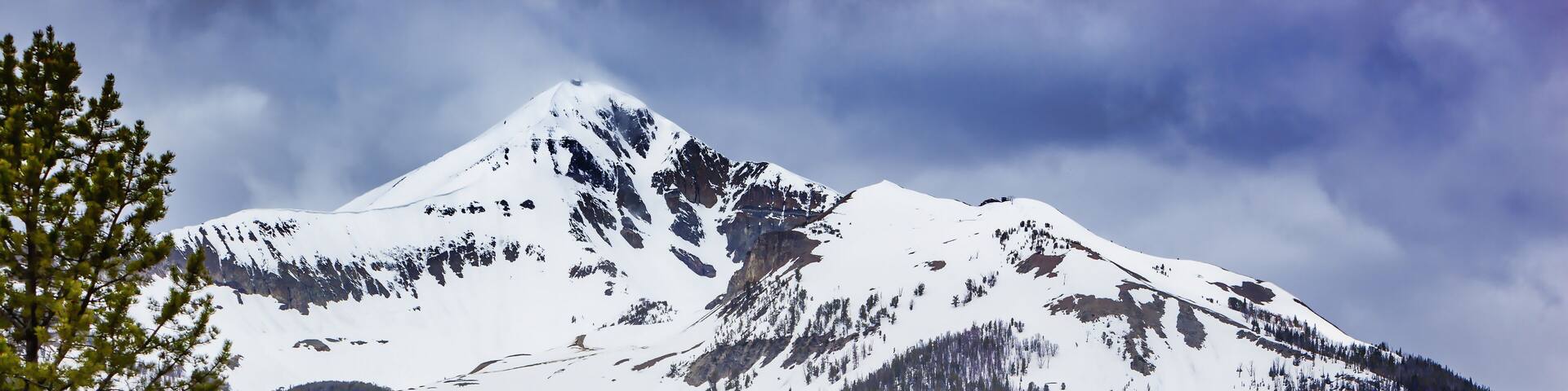 View of Lone Mountain with buildings and pine trees on the foot of the mountain, Big Sky, Montana, USA