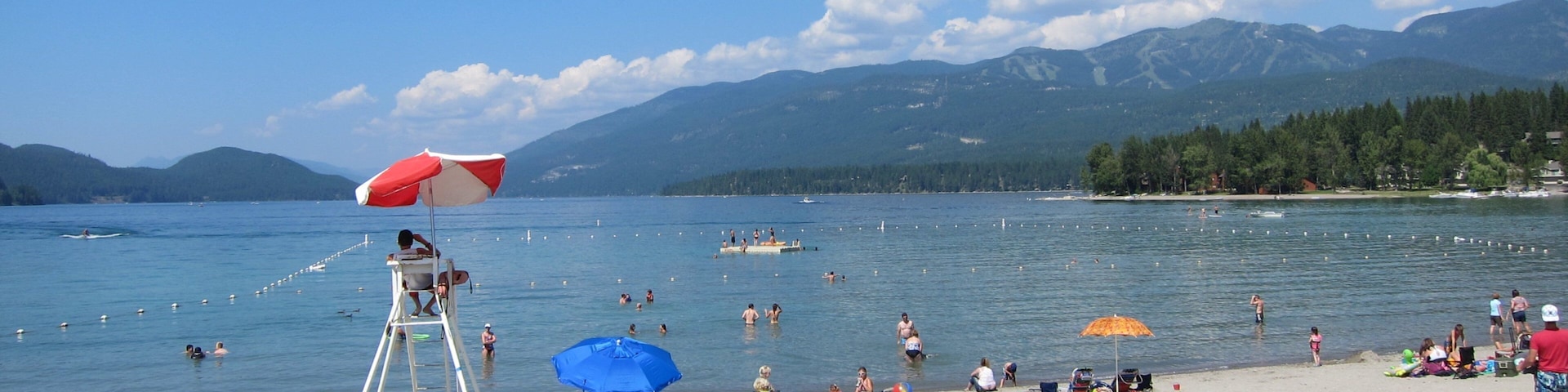 Whitefish Mountain Ski Resort which includes a lake or waterhole and a beach as well as a large group of people