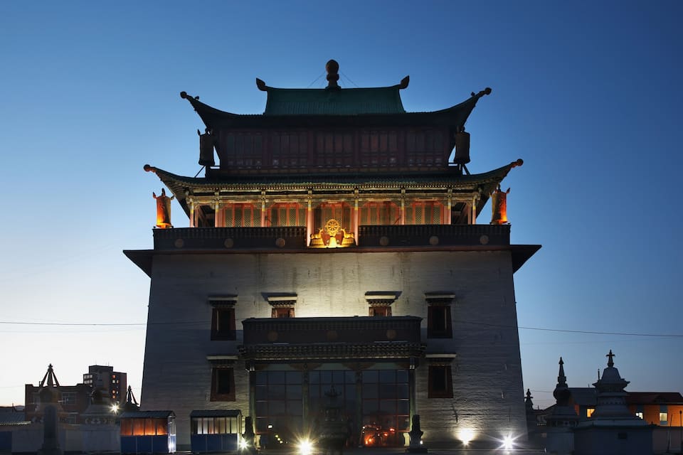 A traditional building with a green roof and ornate decorations, including a bell tower and statues.