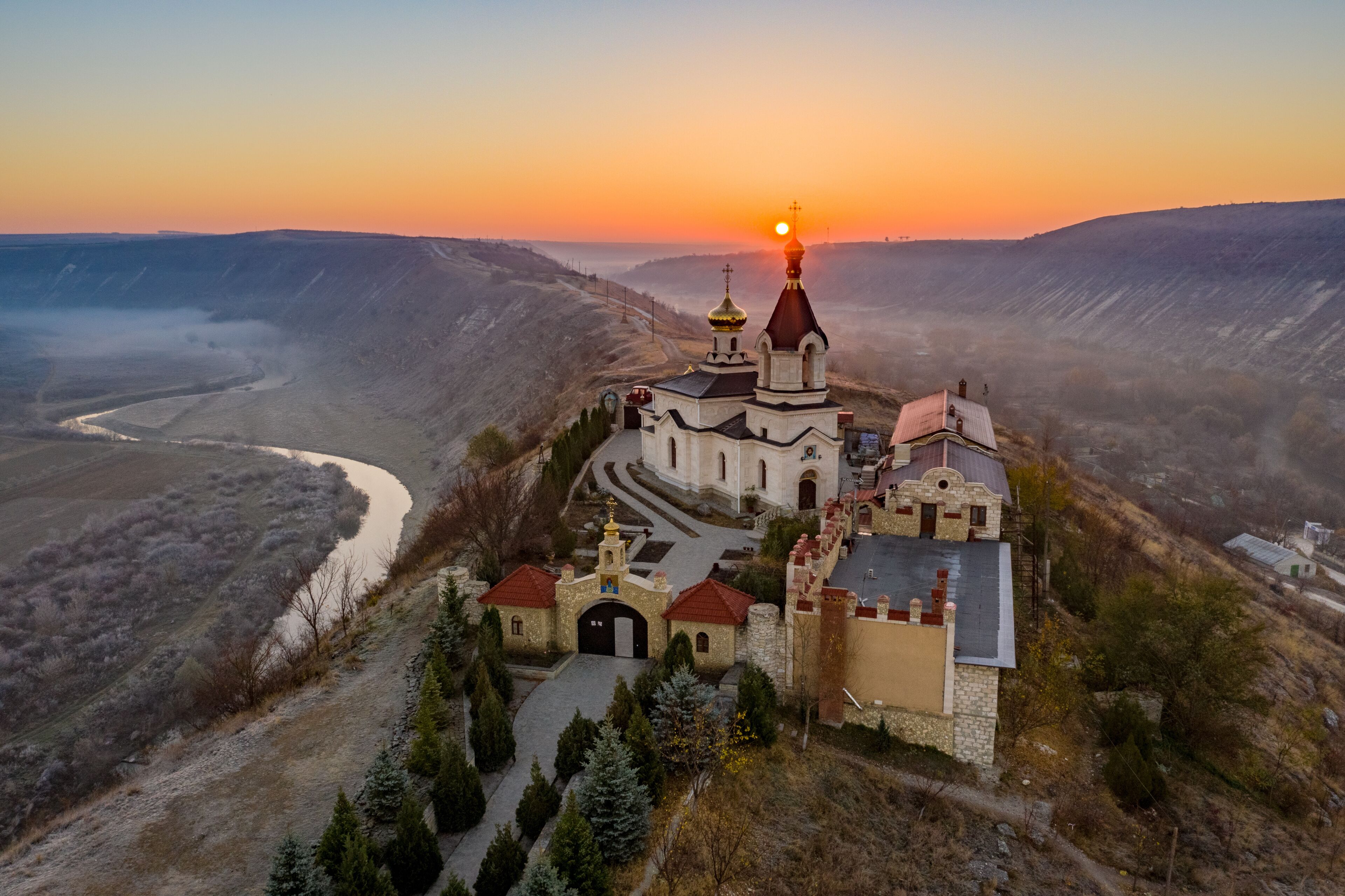 A church with a prominent dome and a river in the valley below.