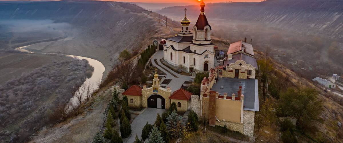 A church with a prominent dome and a river in the valley below.