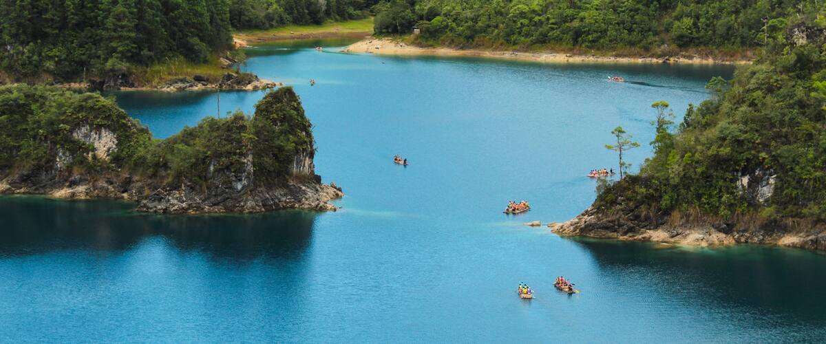 A calm lake surrounded by lush green hills, with several boats on the water.
