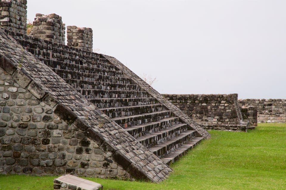 A stone staircase leading up to a stone building with a grassy foreground.