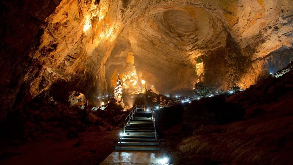 A cave with a staircase leading to a large, illuminated rock formation.