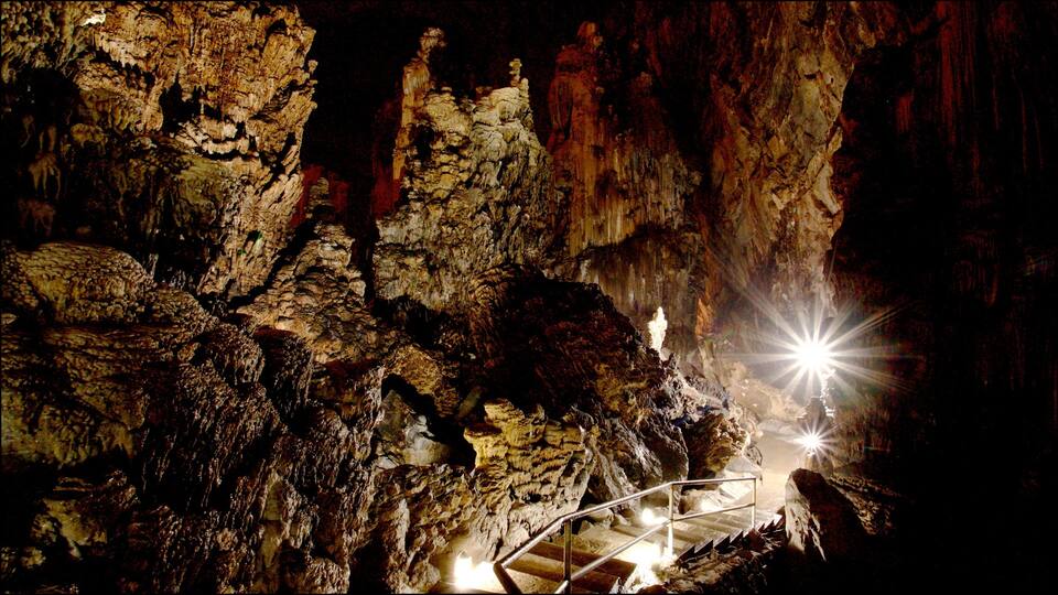 A cave with stalactites and a staircase.