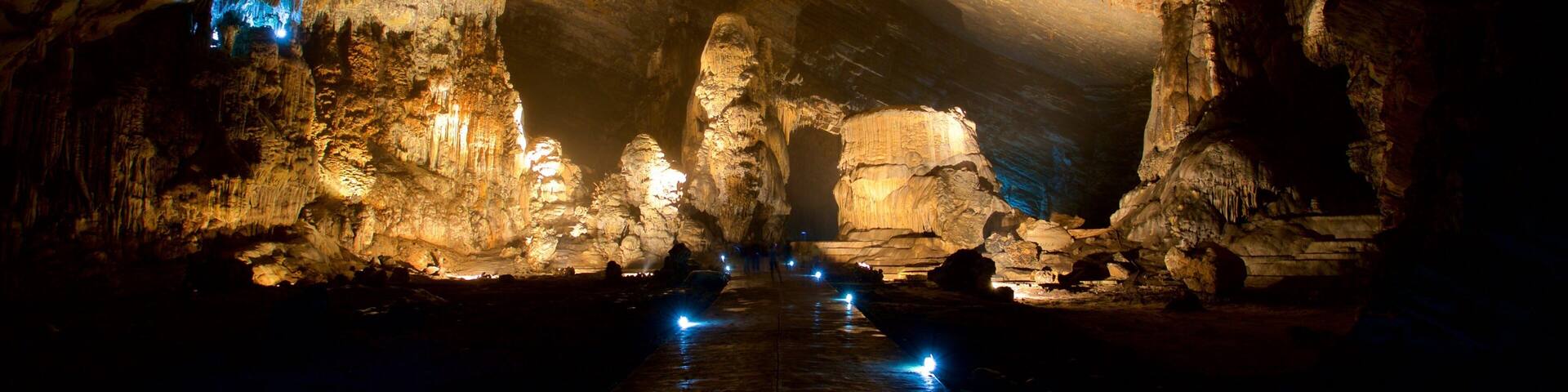A cave with illuminated stalactites and a water channel.