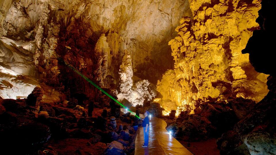 A cave with stalactites and stalagmites, illuminated by a green laser beam.