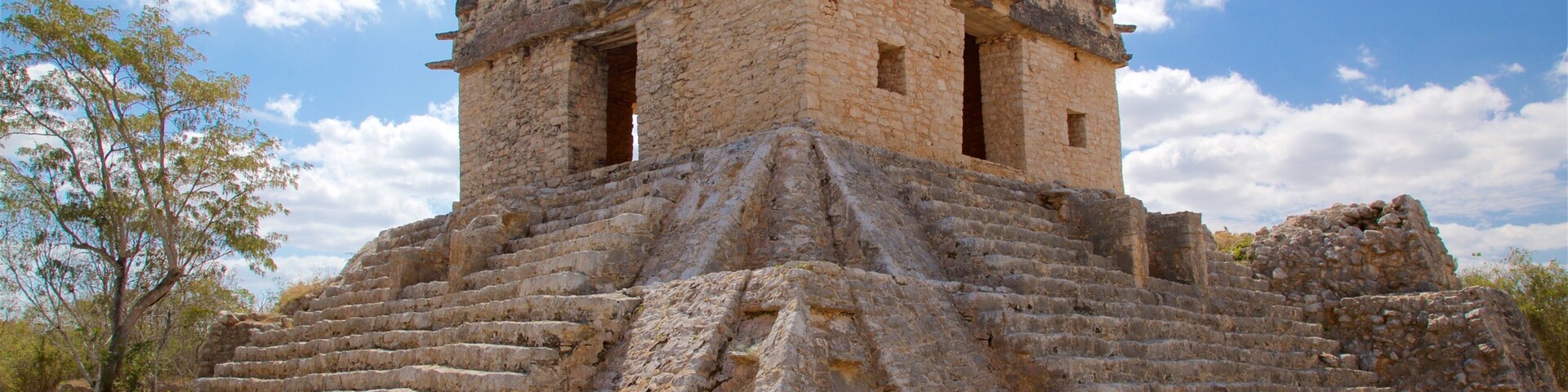 Una estructura piramidal de piedra con un vértice plano y una escalera que lleva hacia ella.