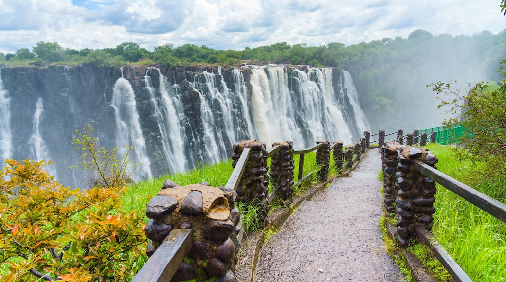 Walking way with view to the dramatic clouds and waterfall at Victoria Falls on the Zambezi River, Zimbabwe, Zambia.