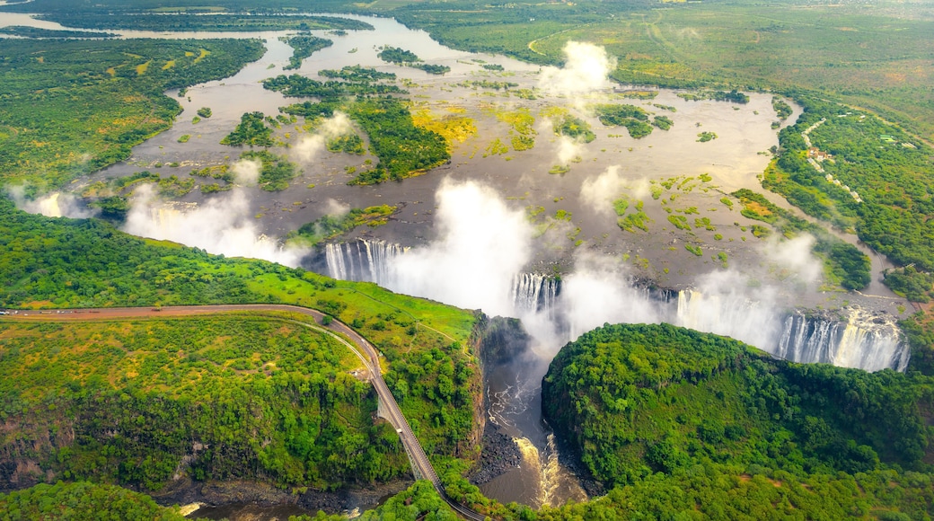 Victoria Falls in Zimbabwe and Zambia, Aerial helicopter photo, green forest around amazing majestic waterfalls of Africa. Livingston Bridge above the river
