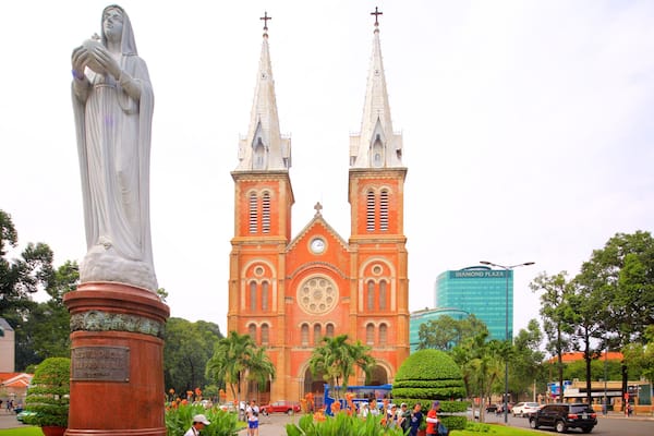 Une statue, une église à deux tours et un bâtiment moderne.