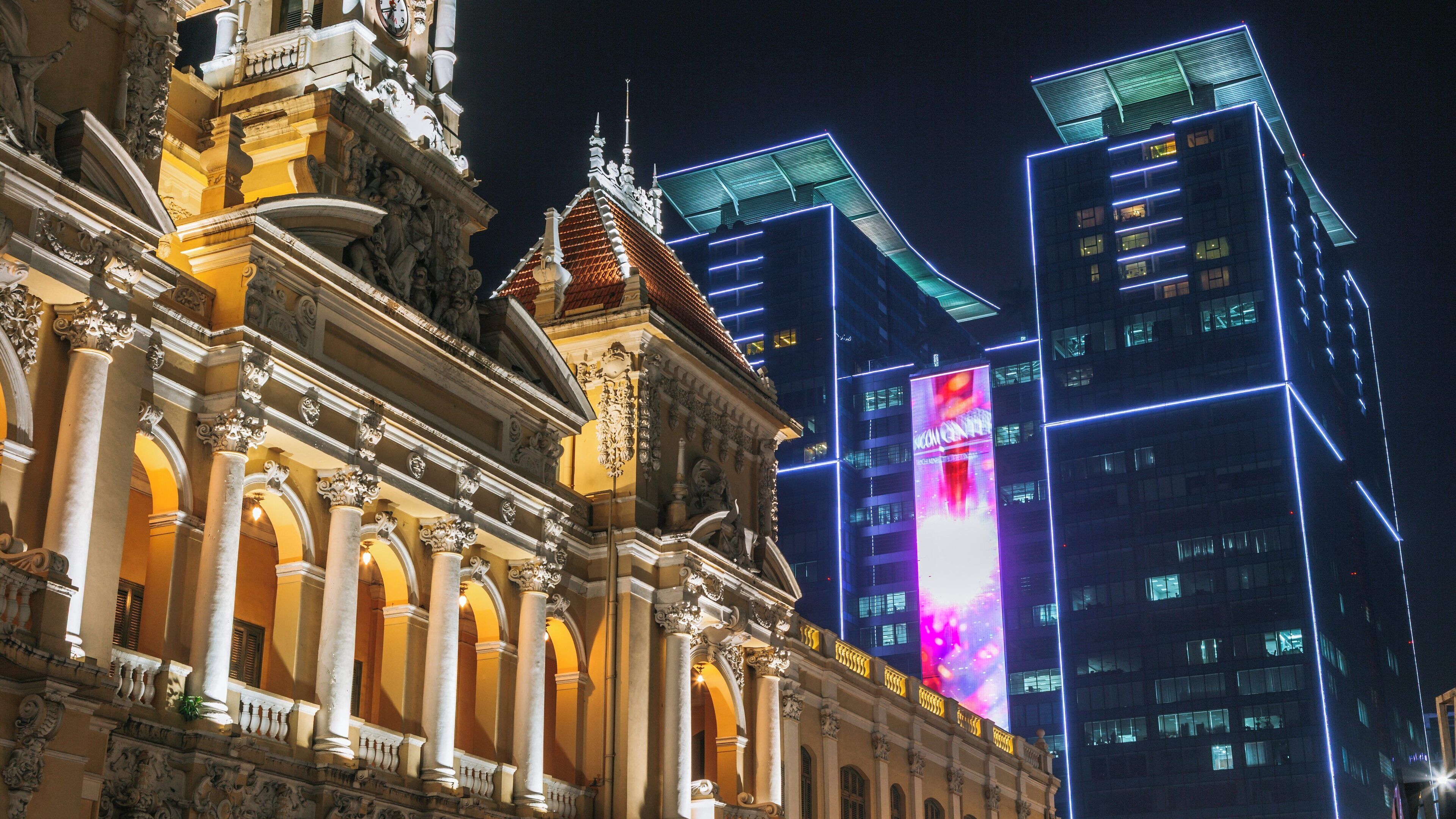 Ho Chi Minh City Hall illuminated at night with modern buildings in District 1, Ho Chi Minh City, Vietnam creating a striking skyline