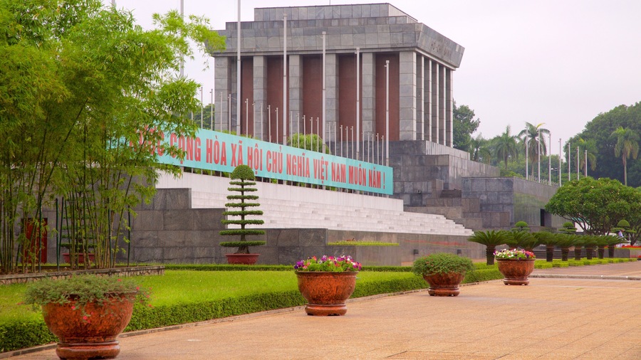A large monument with a staircase leading up to it, surrounded by potted plants and greenery.