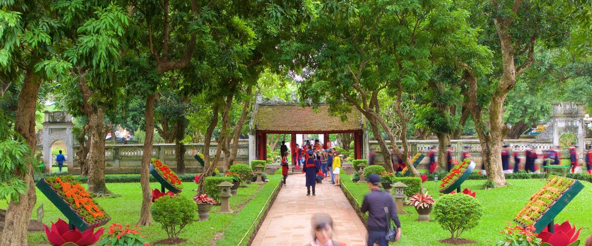A garden pathway leading to a pavilion with people gathered around.