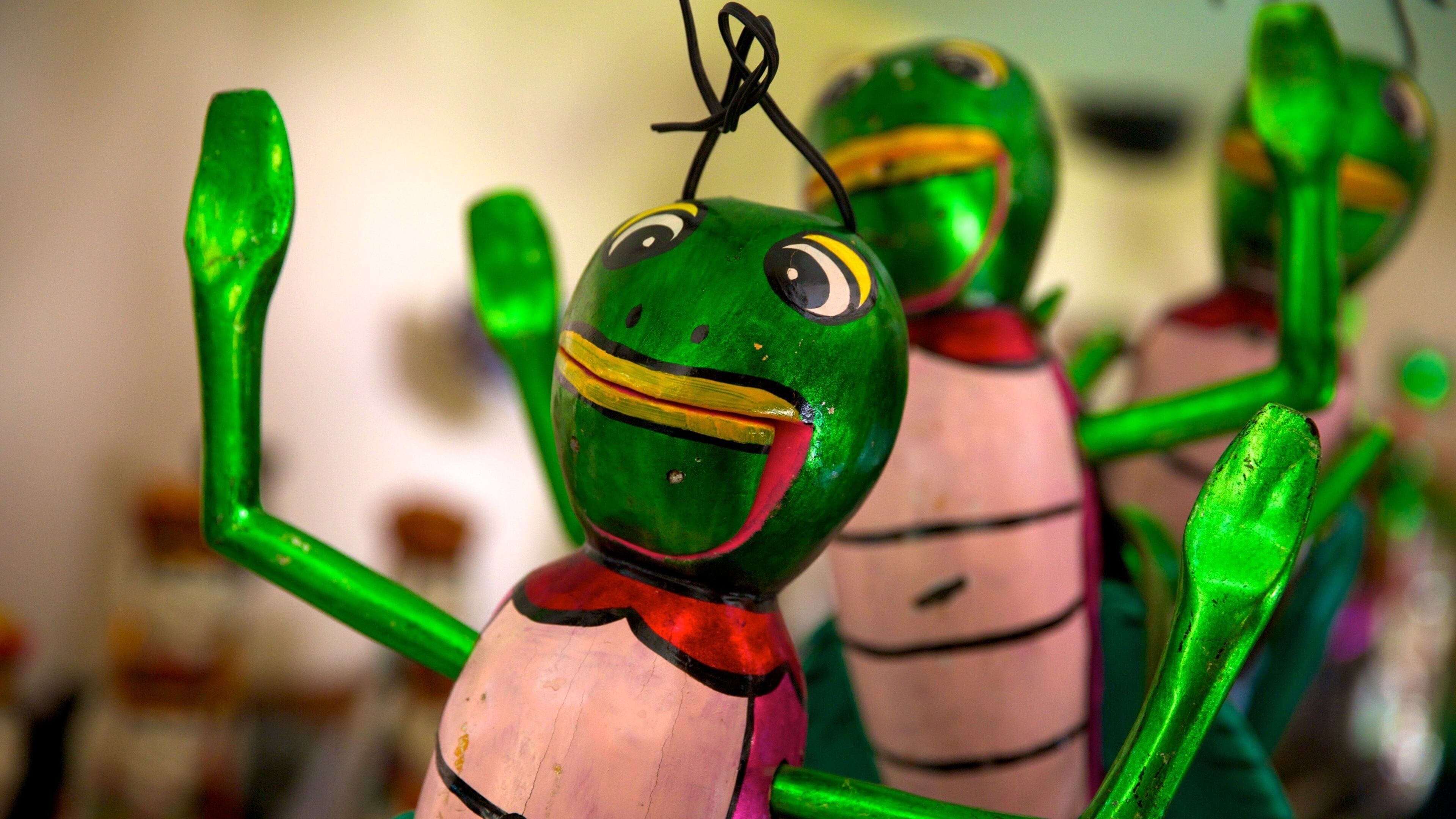 Una figurita de rana con cuerpo verde, collar rojo y una franja amarilla.